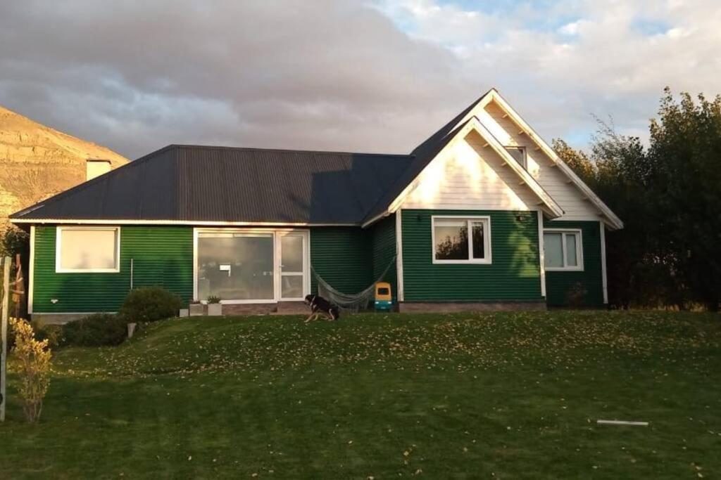 a green house with a dog walking in front of it at Casa Glaciar Patagonia in El Calafate