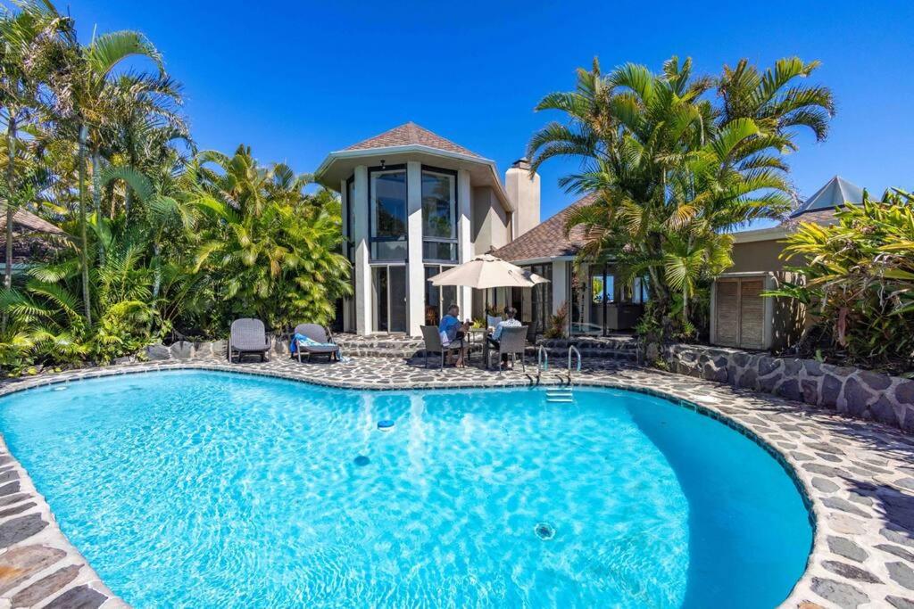 a villa with a swimming pool in front of a house at Opulent Waterfall House with Ocean Views in Haiku, Maui in Huelo