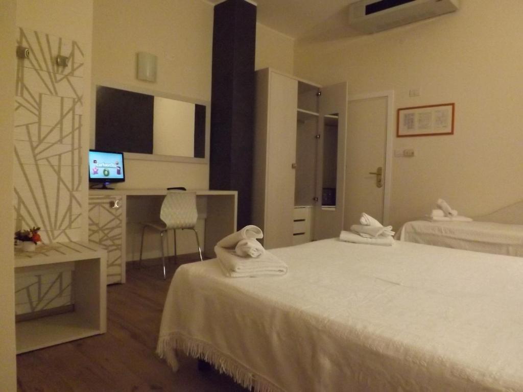 a hotel room with two beds and a desk at Hotel Aurora in Misano Adriatico
