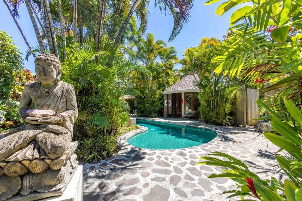 une statue assise près d'une piscine dans une cour dans l'établissement Lavish Cliff House with Ocean Views in Haiku, Maui jungle, à Huelo