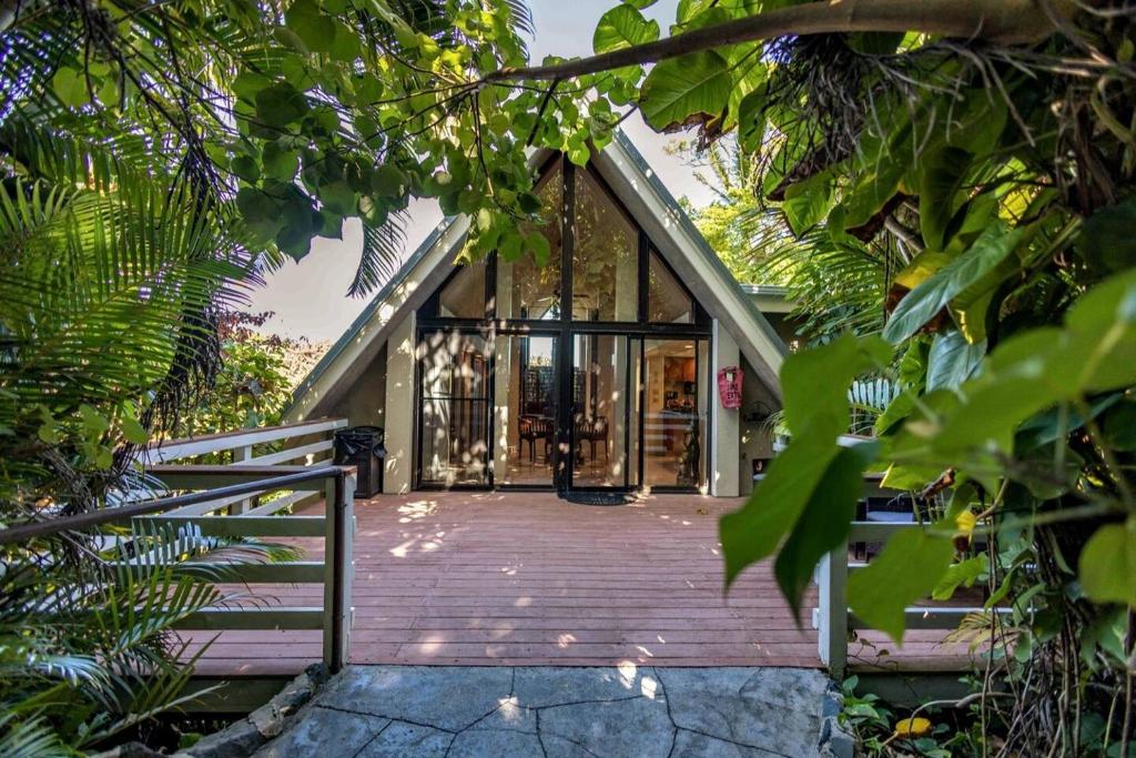 een huis met een houten loopbrug naar een glazen deur bij Jasmine Suite on Lush farm in Haiku, Maui jungle in Huelo