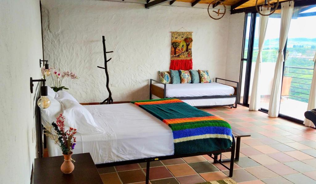 a bedroom with two beds in a room with windows at Casa Luna Hotel Campestre & Spa in San Gil