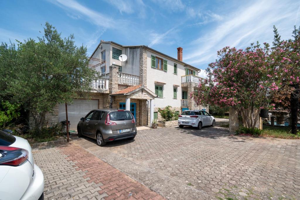 ein Haus mit zwei Autos auf einem Parkplatz in der Unterkunft Triple Room Mrljane 327a in Neviđane