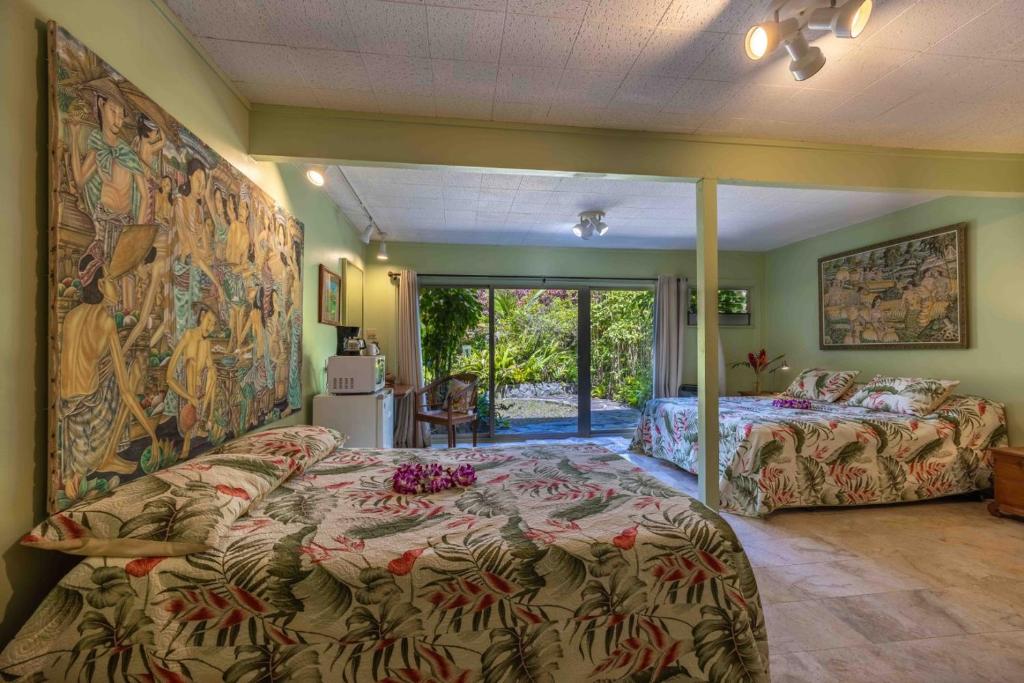 a bedroom with two beds and a large tapestry at Plumeria Room on a Lush Farm on Maui's North Shore in Huelo