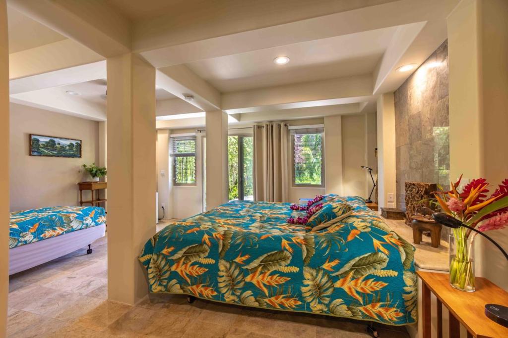 a bedroom with a bed with a blue comforter at Gardenia Room on Tropical Lush Farm in Haiku, Maui in Huelo