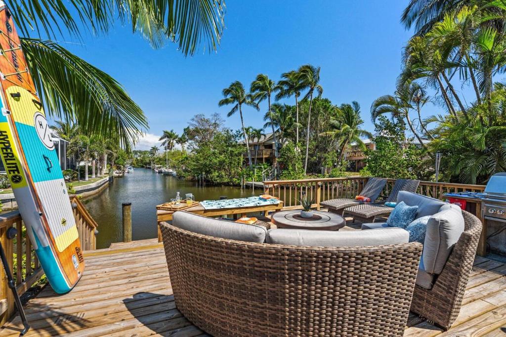 a deck with wicker furniture and a view of a canal at Boaters Bayshore Bungalow in Naples