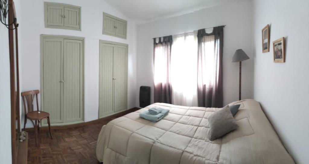 a white bedroom with a bed and a chair at Casa/ Villa General Belgrano in Villa General Belgrano