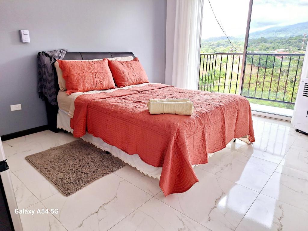 ein Schlafzimmer mit einem Bett mit einer roten Decke und einem Fenster in der Unterkunft Victoria House-Sun View Hostel in San Isidro