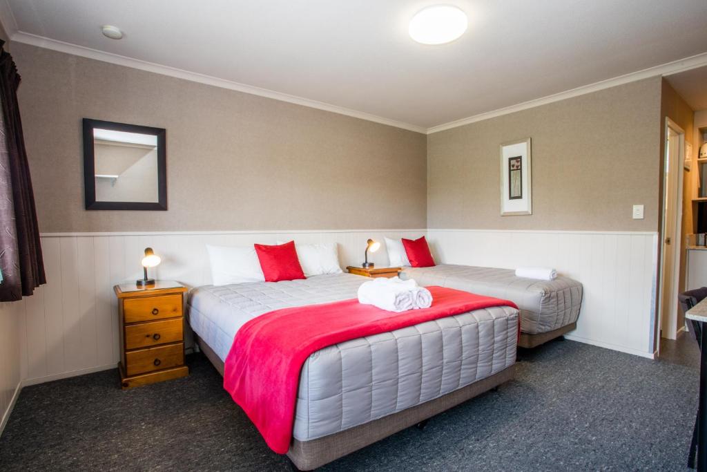 een slaapkamer met 2 bedden met rode en witte kussens bij Te Anau Top 10 Holiday Park and Motels in Te Anau