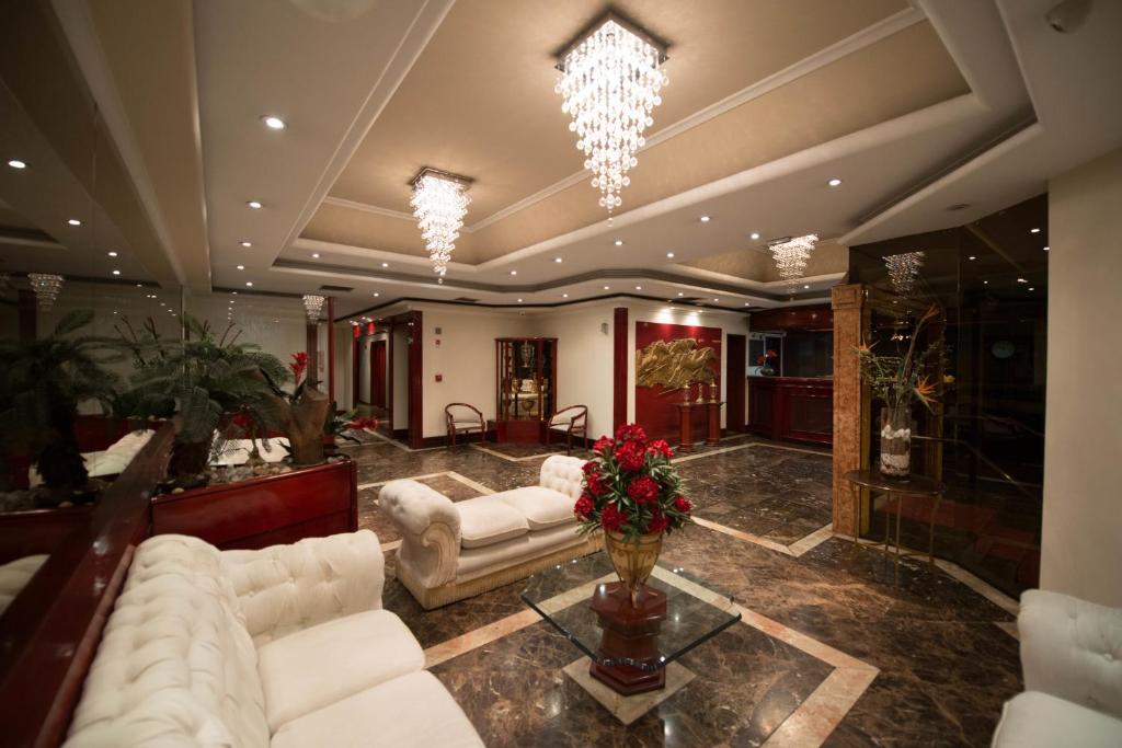 a living room with white couches and flowers on a table at Maxim Plaza Hotel in Juiz de Fora