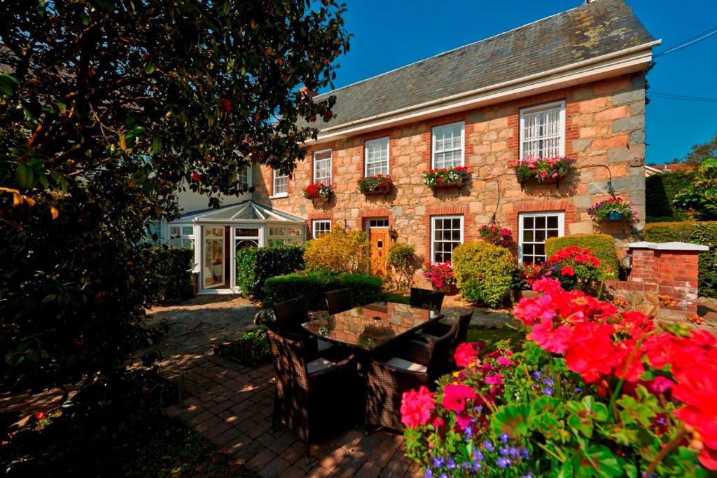 uma casa de tijolos com flores em frente em La Barbarie Hotel em St Martin Guernsey