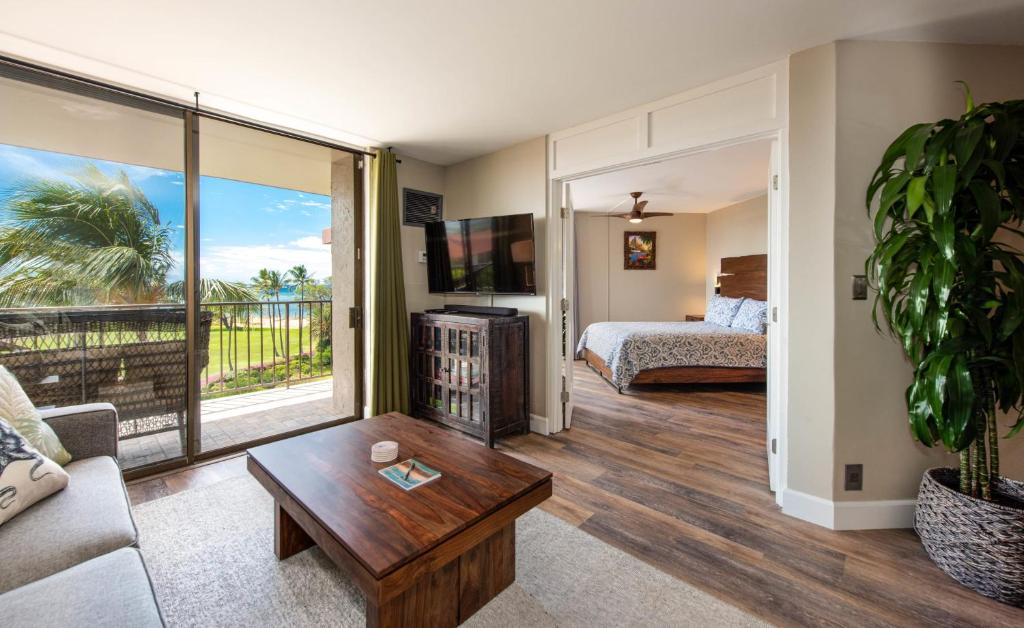 een woonkamer met een bank, een bed en een tafel bij Refined Oceanfront Retreat in Kihei