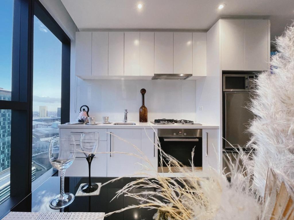 Una cocina con gabinetes blancos y vista a la ciudad. en Prima Tower 1B Apt by GoodLive, en Melbourne