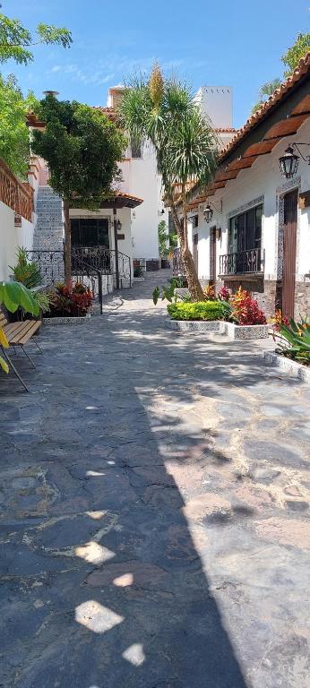 une passerelle dans une cour avec des palmiers et un bâtiment dans l'établissement Casa Yollotzin, à Ajijic