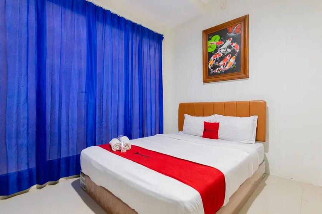 a bedroom with a large bed with blue curtains at RedDoorz @ Bukit Palma Surabaya in Kendung