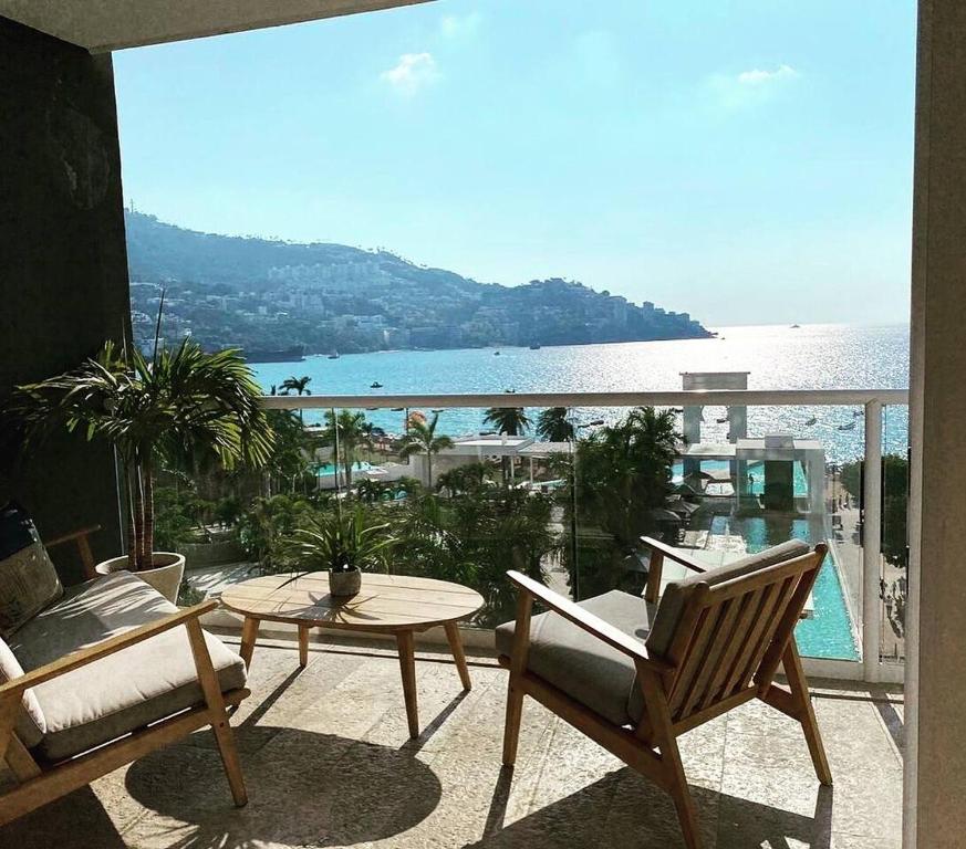 a balcony with a table and chairs and a view of the ocean at LECLUB ACAPULCO in Acapulco