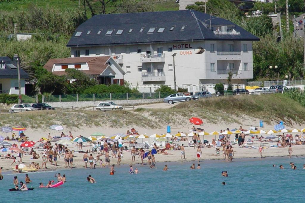 a group of people on a beach in the water at Hotel Duna in Portonovo