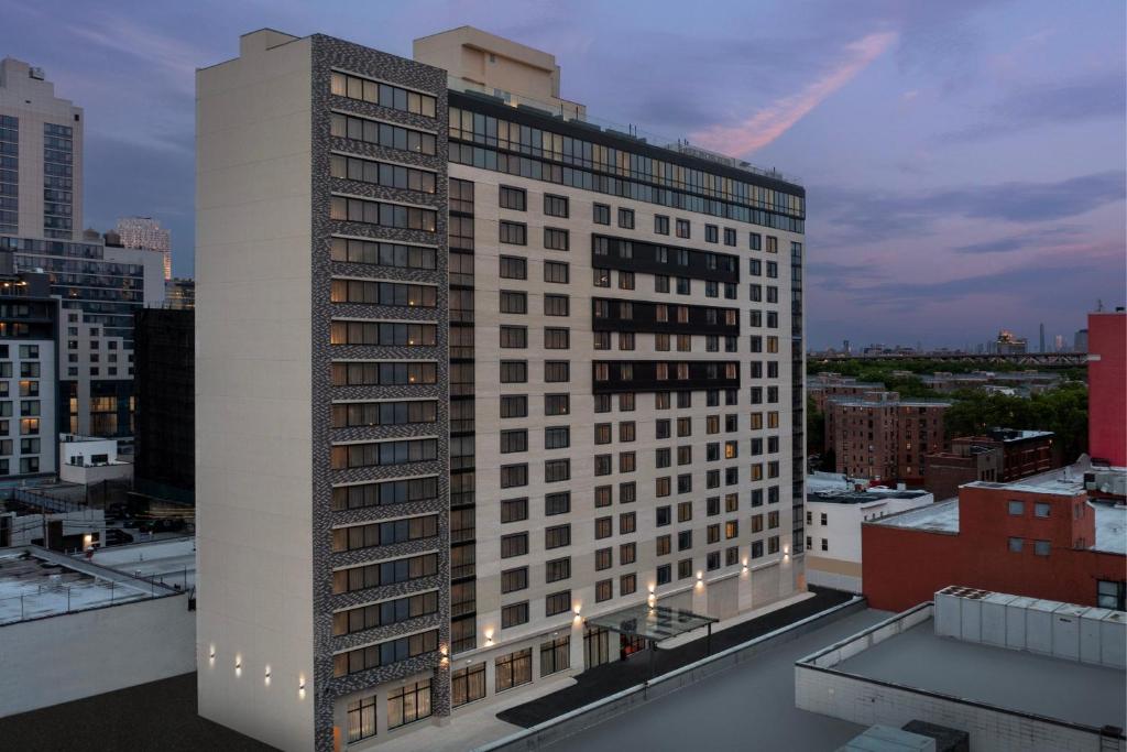 un grand bâtiment blanc au sommet d'une ville dans l'établissement SpringHill Suites by Marriott New York Queens, à Queens
