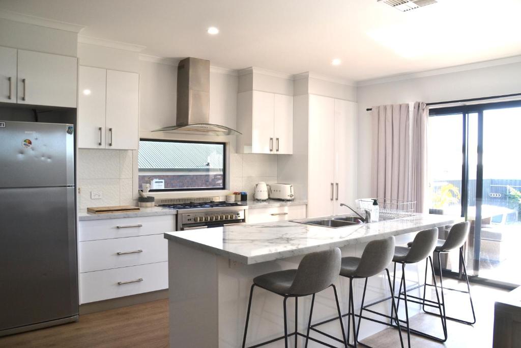 a kitchen with white cabinets and a island with bar stools at The Baltimore House - Family Getaway in Port Lincoln