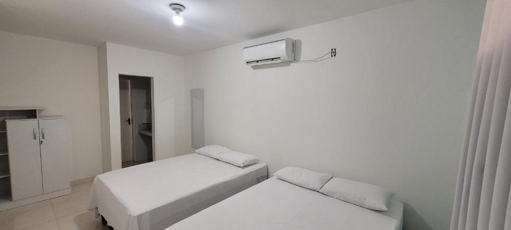 a white room with two beds and a tv at Aquarela do Sertão in Piranhas