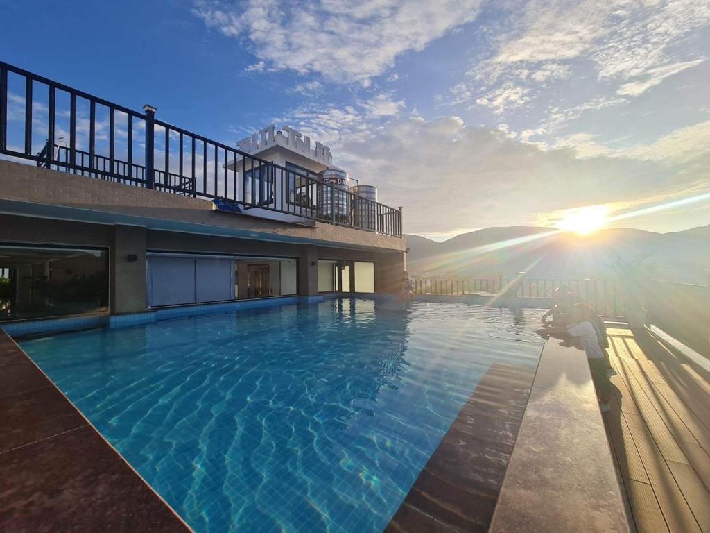 a pool on top of a building with the sun setting at Tuấn Ninh Hotel II in Con Dao