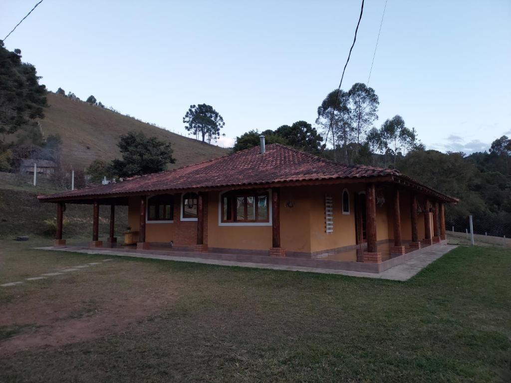 una pequeña casa en un campo al lado de una colina en Casas Bueno en Camanducaia