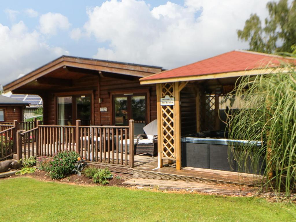a wooden cabin with a hot tub on a deck at Cornfield Lodge in Northallerton