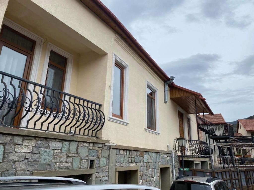 a building with a balcony with cars parked in front of it at Guesthouse David in Mtskheta