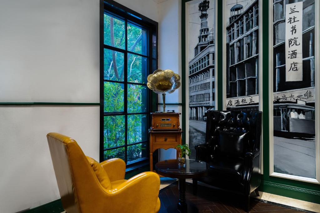 een woonkamer met 2 stoelen, een tafel en een raam bij Hangzhou Lanshe hotel in Hangzhou