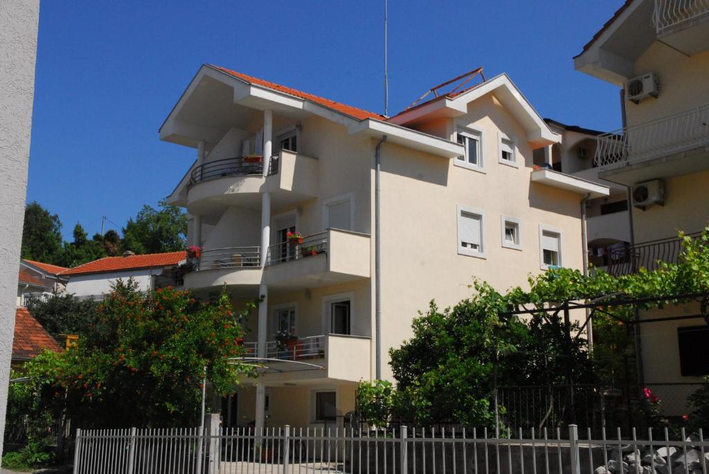 a white building with a fence in front of it at Apartments Teodo in Tivat
