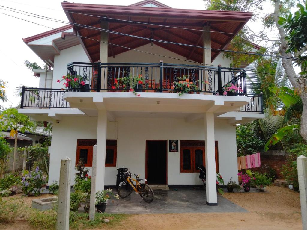 a house with a balcony with flowers on it at Villa Chaya in Hikkaduwa
