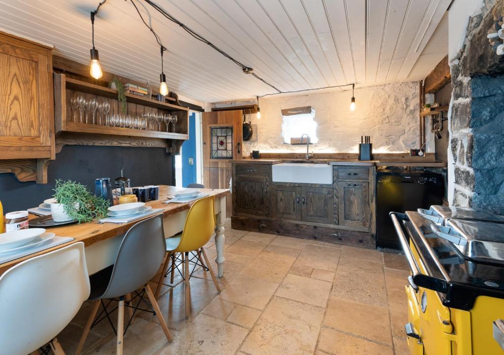 a kitchen with a long table and chairs in a room at Hideaway Tyn Llan in Bryncroes