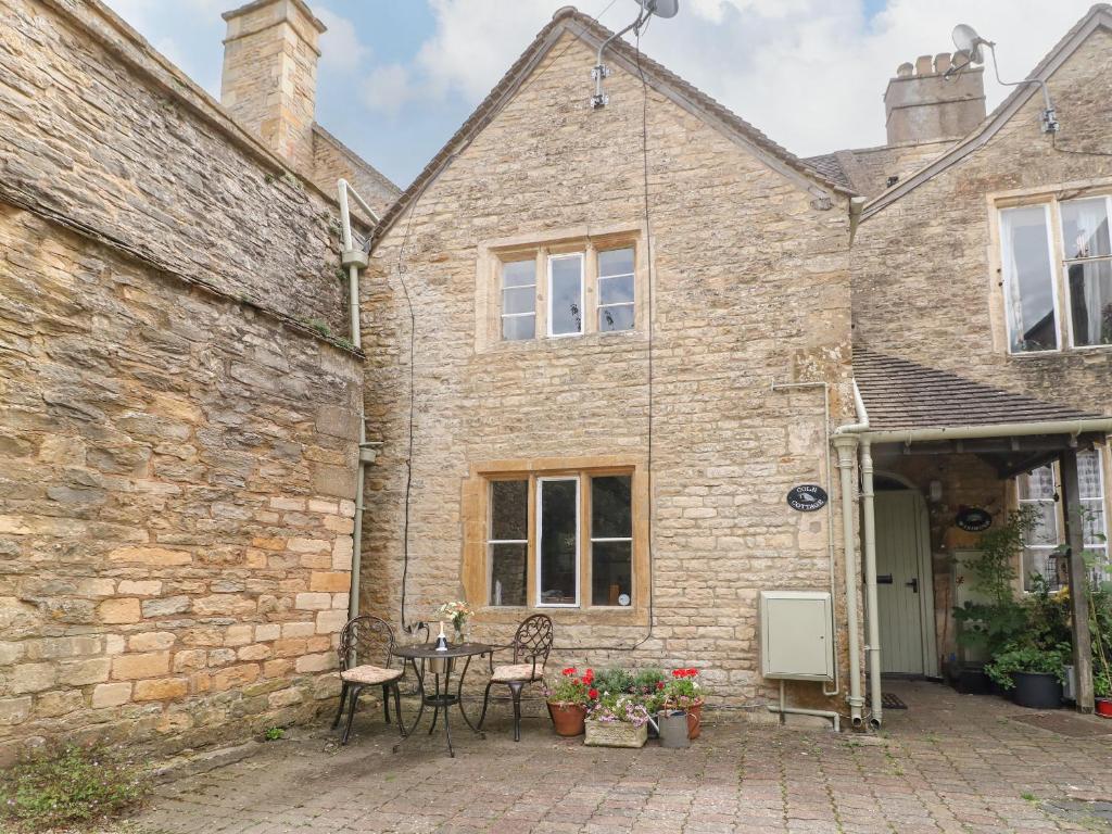 a stone house with a patio in front of it at Coln Cottage in Stow on the Wold