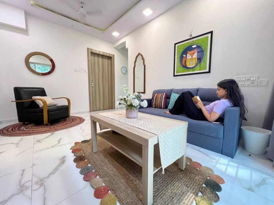 a woman sitting on a blue couch in a living room at Jastcon, 19th Rd, Khar, Ambedkar Colony by Connekt Homes in Mumbai