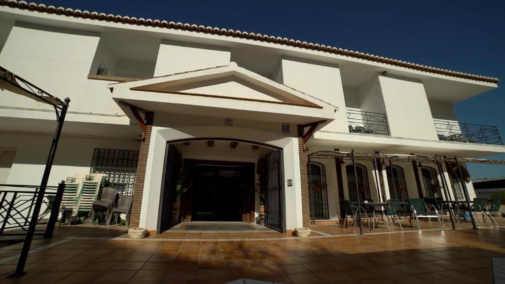 a white building with a porch and chairs at Balneario de Alicún de las Torres in Villanueva de las Torres