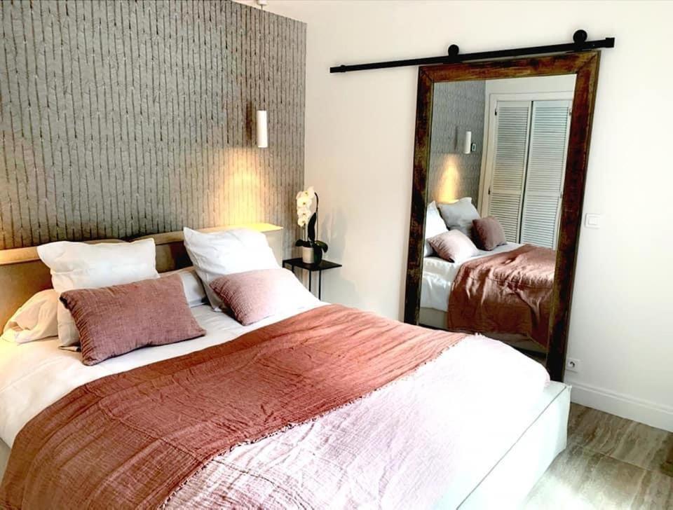 ein Schlafzimmer mit einem großen Bett und einem Spiegel in der Unterkunft Villa Couloubrier in Sainte-Maxime