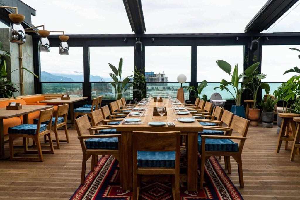 a dining room with tables and chairs and windows at Orbi Sea Towers in Batumi