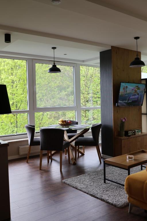 salon ze stołem, krzesłami i oknami w obiekcie Keller Apart - Kurort Kozubnik K25 w mieście Porąbka