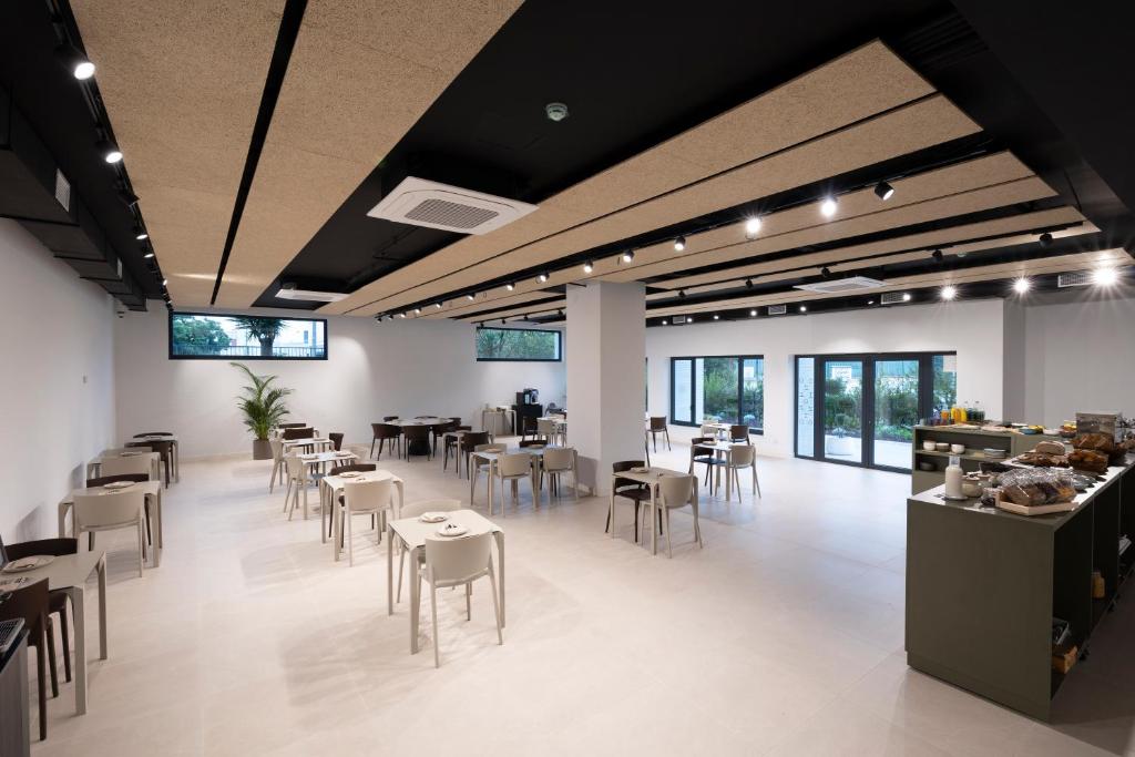 a dining room with tables and chairs and windows at Hotel H4 Cangas 3 Superior in Cangas de Morrazo
