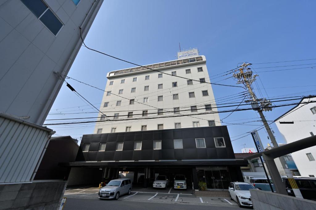 和歌山的住宿－和歌山縣第一核電站富士酒店，一座高大的白色建筑,汽车停在停车场