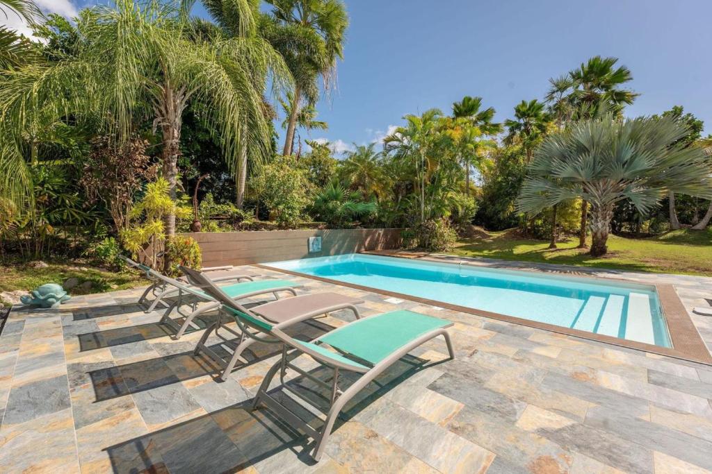 einen Pool mit Chaiselongues neben einem Pool in der Unterkunft Villa Ma Vie La in Saint-François