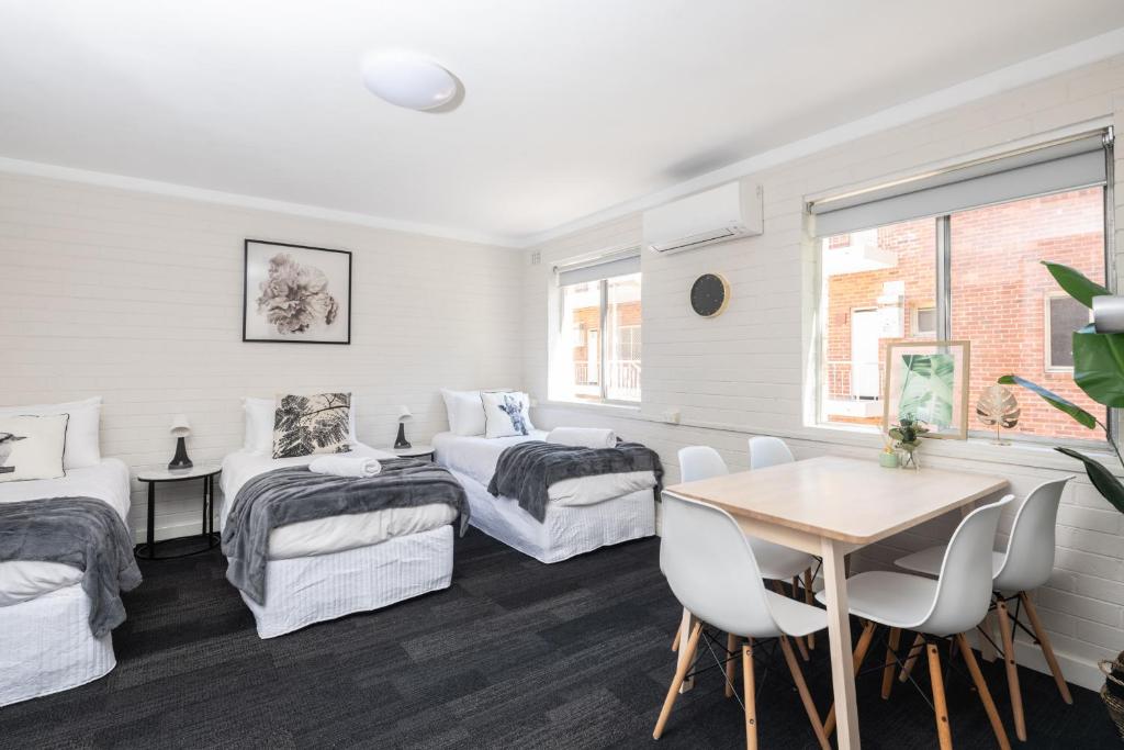 Habitación con 2 camas, mesa y sillas en Central location 2 bdrm free parking and WiFi, en Perth