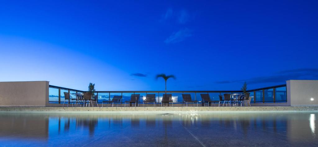 una piscina por la noche con luces azules en Promenade Prime Itaboraí, en Itaboraí