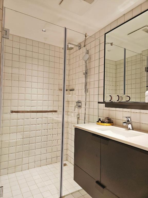 a bathroom with a shower and a sink and a mirror at base-Beijing Wangfujing Serviced Apartment- in Hutong &Bike rental &Close to Forbidden City, Tian'anmen Square &Subway nearby &Free coffee &Washing machine,Kitchen &Restaurant discount &English speaking &High speed free WiFi in Beijing