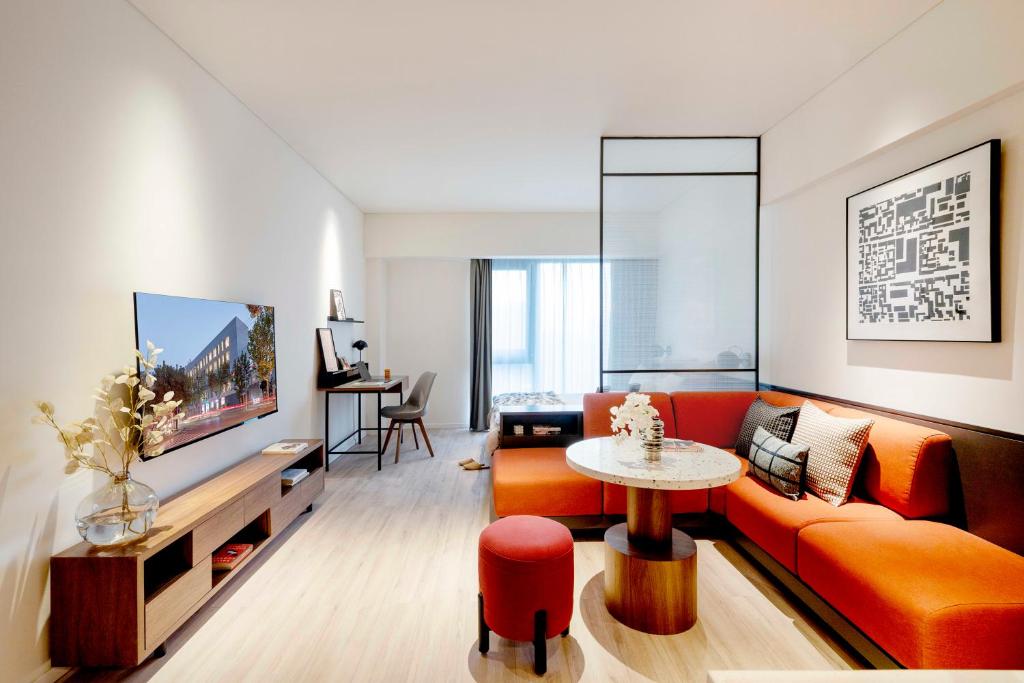 a living room with an orange couch and a table at base-Beijing Wangfujing Serviced Apartment in Beijing