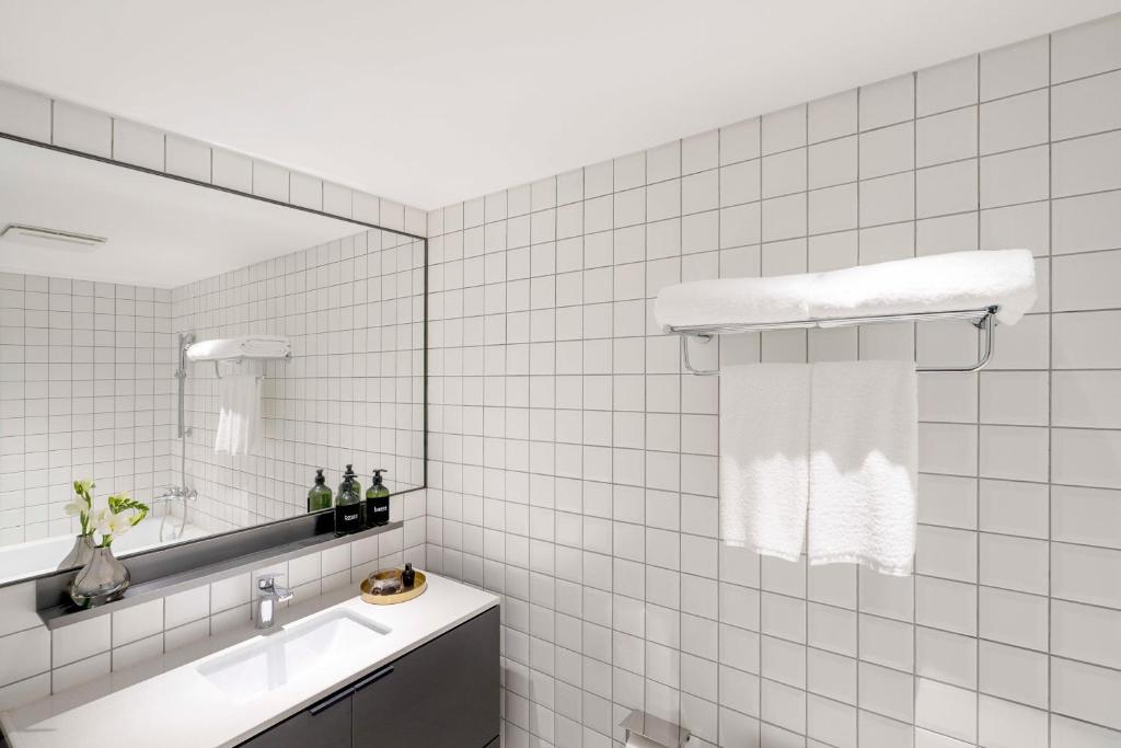 a white tiled bathroom with a sink and a mirror at base-Beijing Wangfujing Serviced Apartment- in Hutong &Bike rental &Close to Forbidden City, Tian'anmen Square &Subway nearby &Free coffee &Washing machine,Kitchen &Restaurant discount &English speaking &High speed free WiFi in Beijing