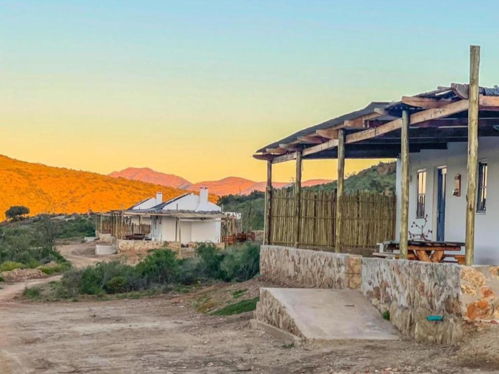 una casa en el desierto con una puesta de sol en el fondo en Klein Doorn Farm Stay, en Oudtshoorn