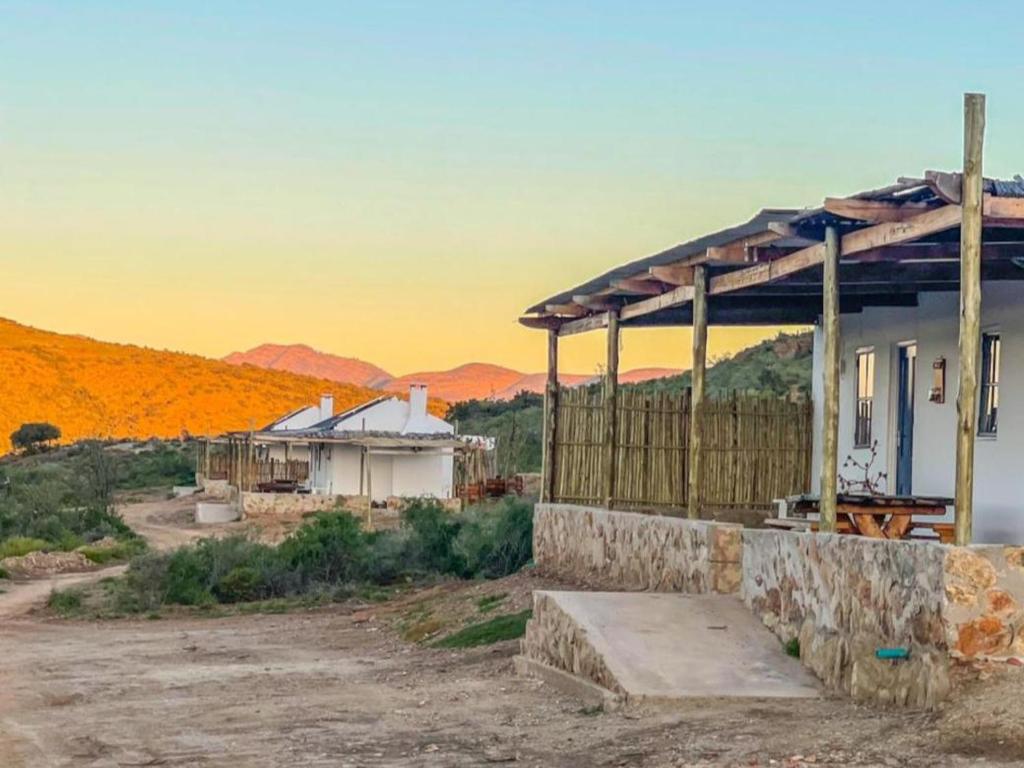 a house in the desert with a sunset in the background at Klein Doorn Farm Stay in Oudtshoorn