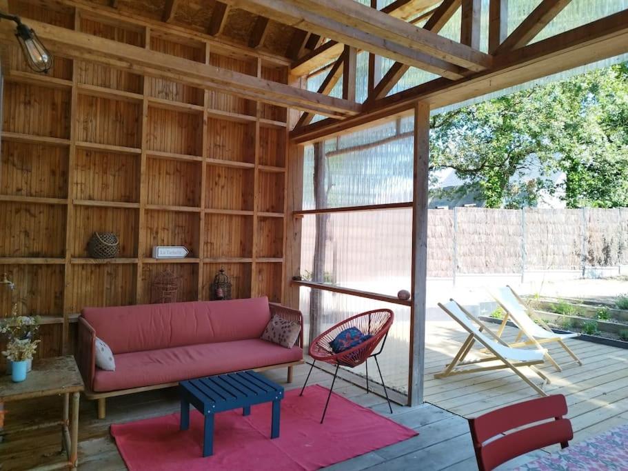 een woonkamer met een rode bank en een stoel bij Le charme du bois - 8 à 10 personnes- Maison entière in La Turballe