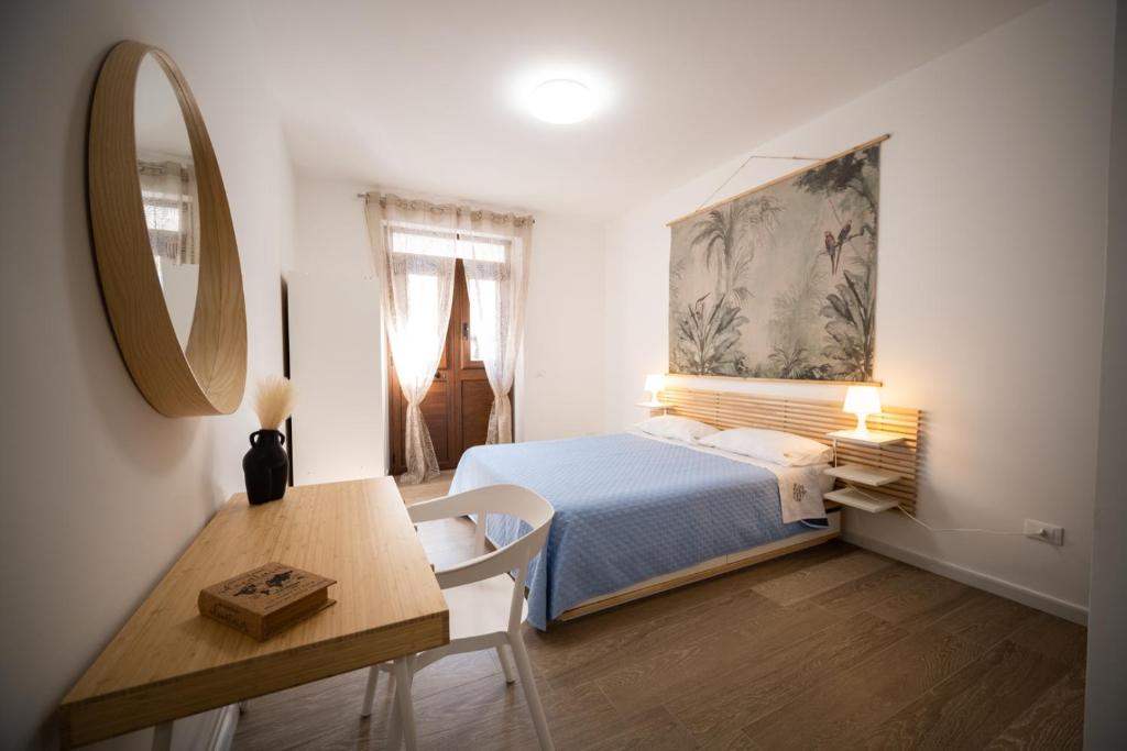 1 dormitorio con cama, mesa y espejo en Matilde’s Holiday House en Terrasini